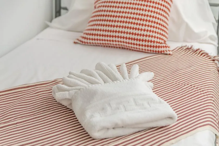 A neatly made bed with folded white towels and red-striped bedding.