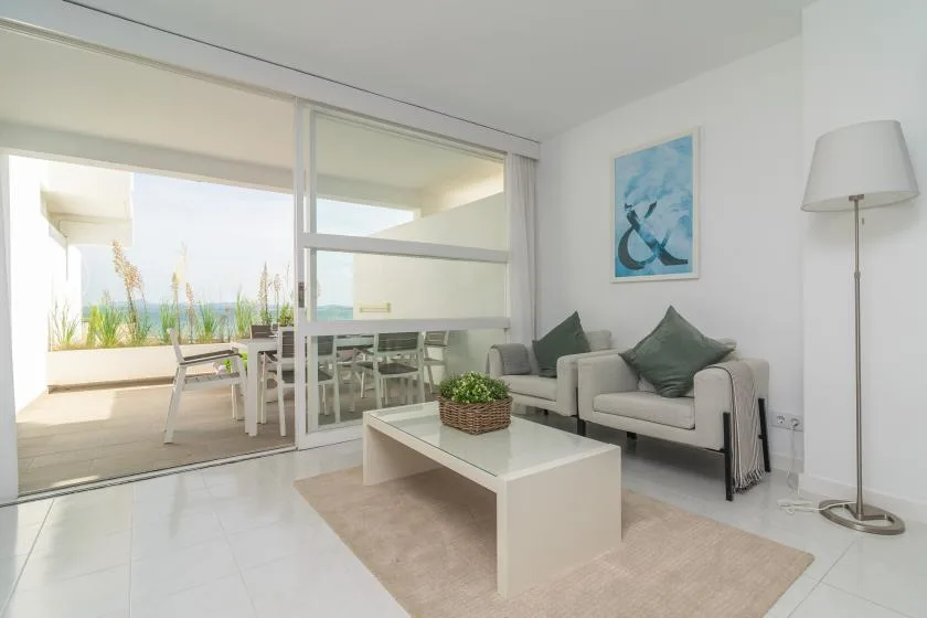 A bright living room with seating, a coffee table, and sliding glass doors.