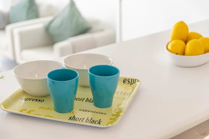 A bright dining area with colorful cups on a tray and lemons on the counter.