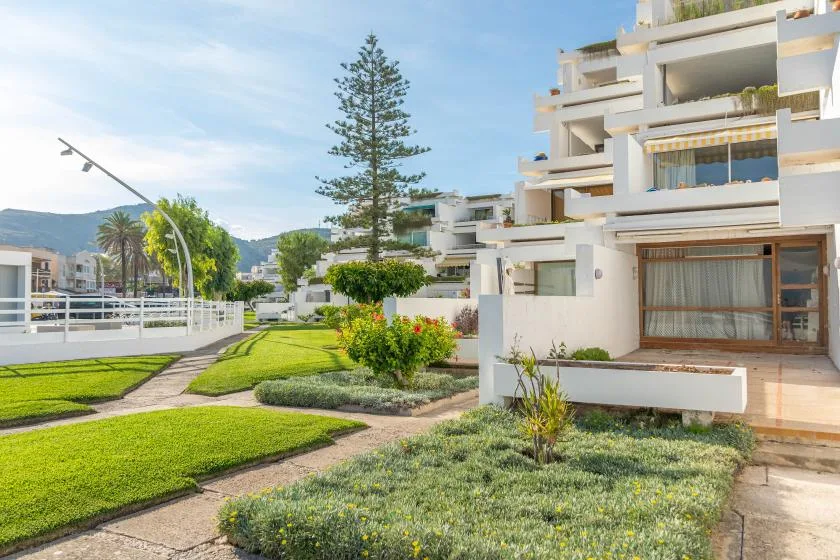 Modern apartment buildings overlook landscaped lawns and a paved walkway.