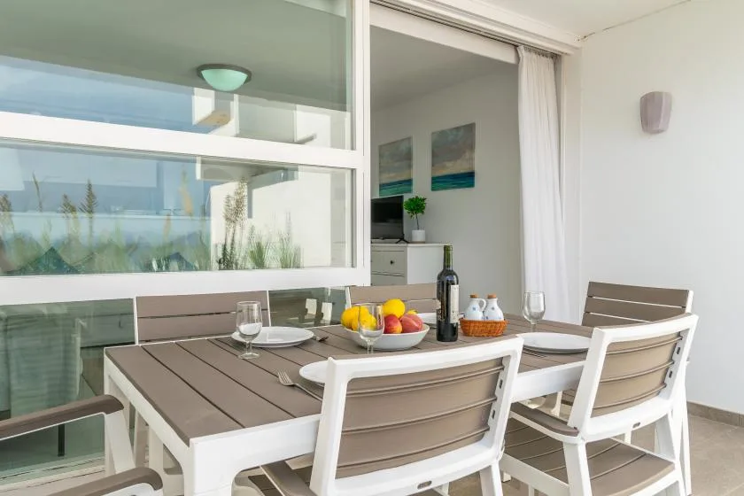 A patio dining area with a table set with fruit and white seating.