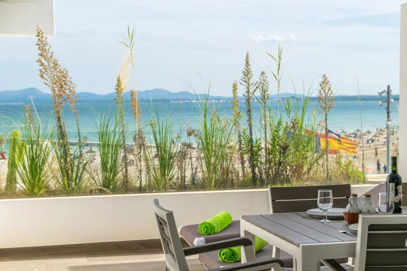 A patio dining area overlooks the beach and ocean through tall grasses.