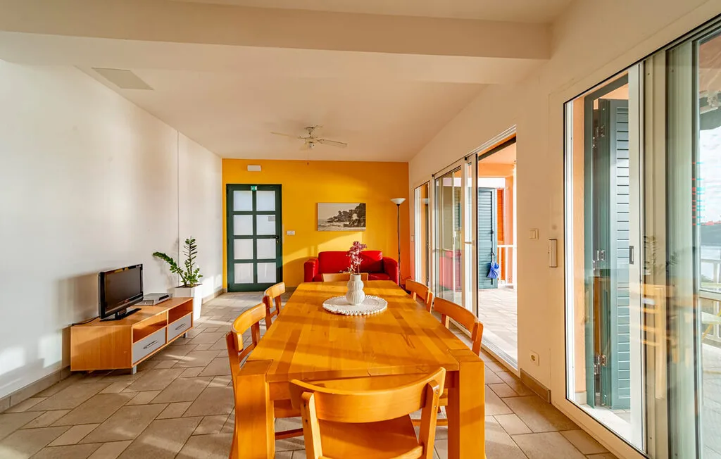 A dining area with a long wooden table and seating beside large glass doors.