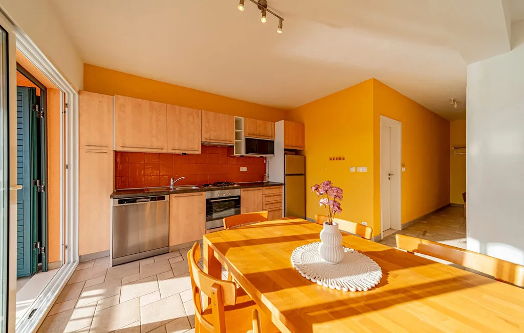 A bright kitchen and dining area with wooden tables and light-colored cabinetry.