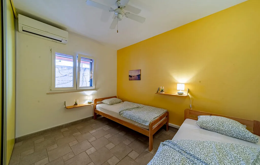 A bedroom with two beds, a window, and yellow walls.