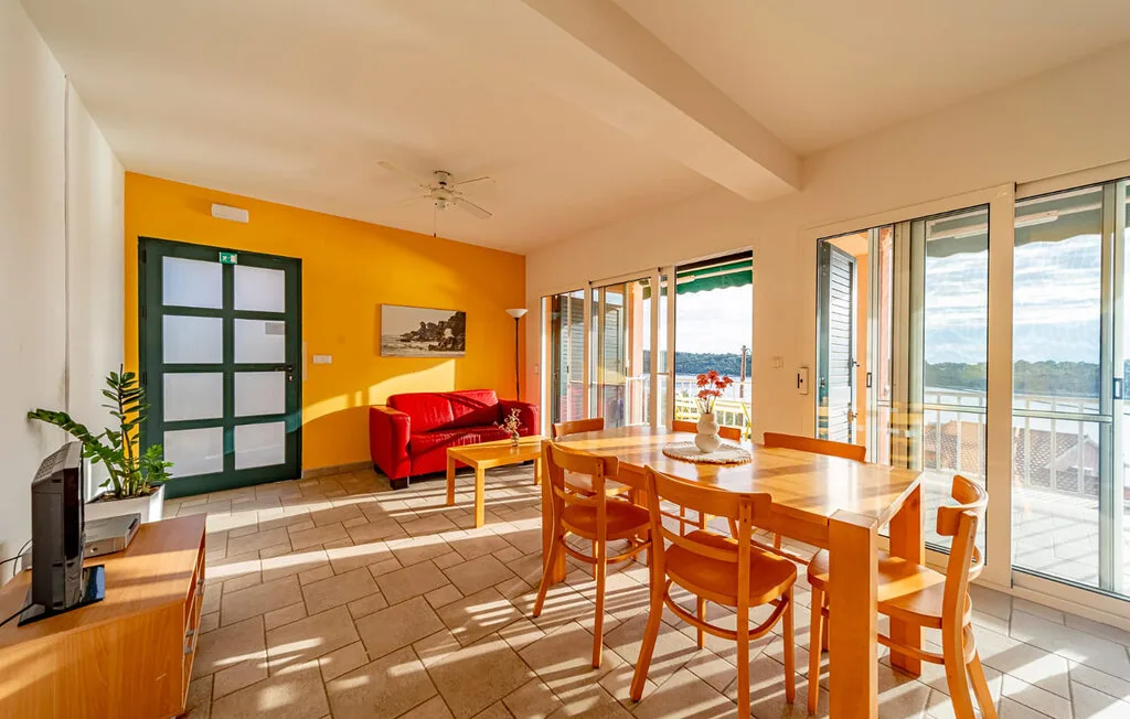 A bright dining and living area with wooden seating and large glass doors.