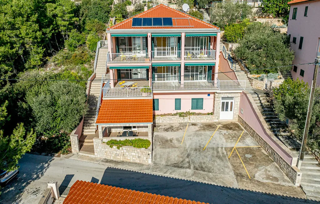 A multi-story house with balconies and a paved driveway.