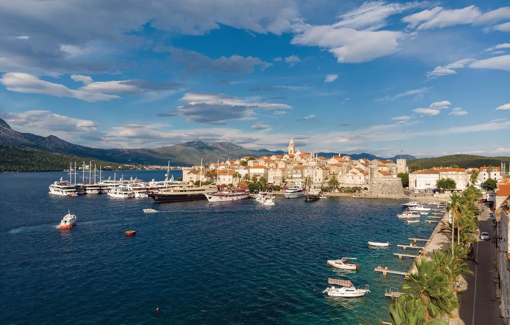 A coastal town stretches along a harbor with boats on the water.