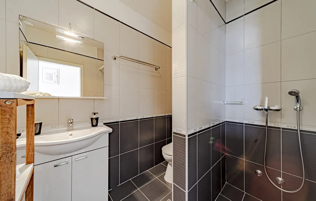 A tiled bathroom with a sink, mirror, and shower.