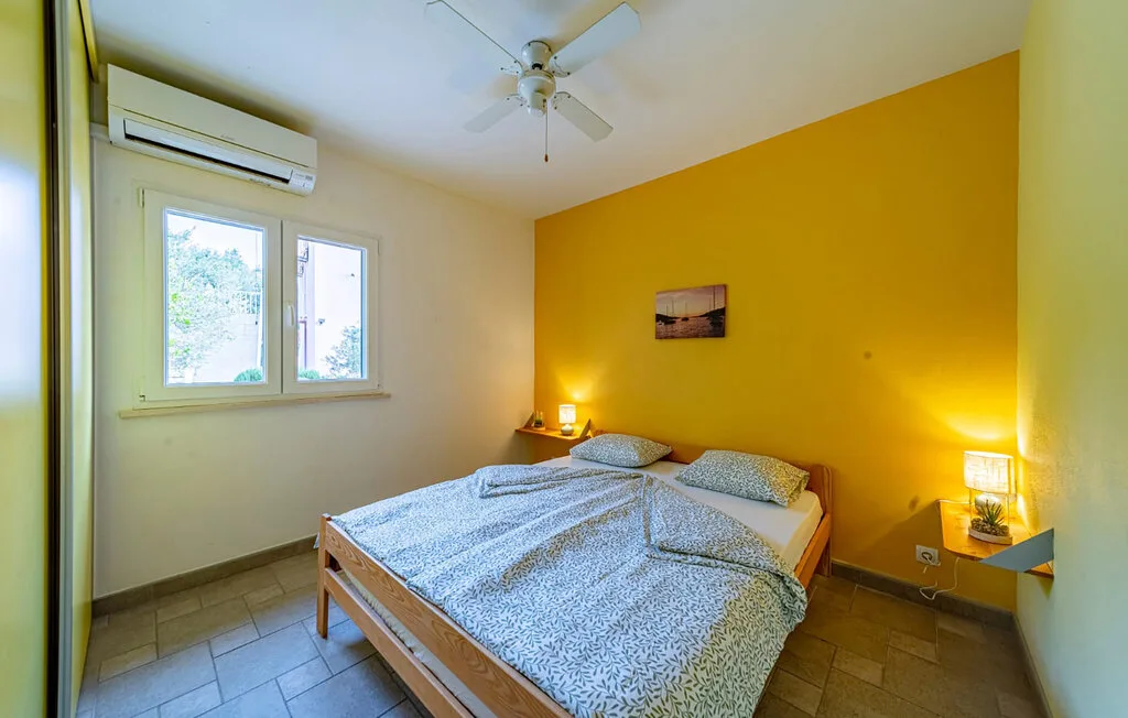 A bedroom with a double bed, bedside tables, and a yellow accent wall.