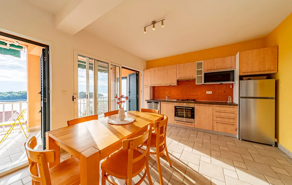 A bright dining area opens onto a balcony beside a kitchen.