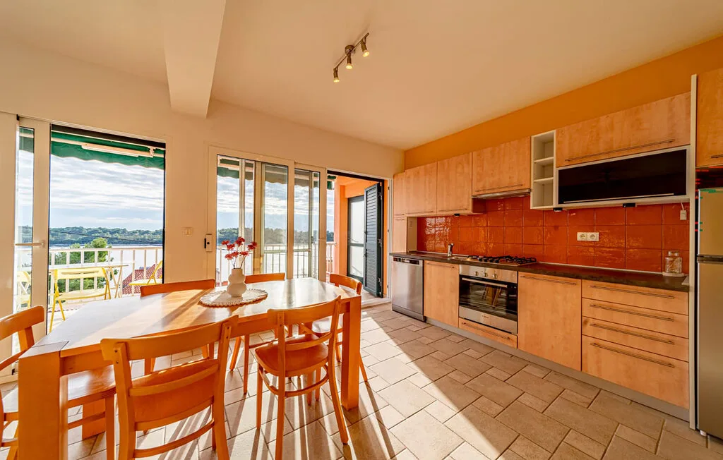 A bright kitchen and dining area with wooden cabinets and a table by the windows.