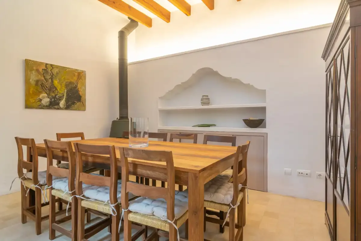 A dining area with a wooden table, chairs, and a built-in wall shelf.