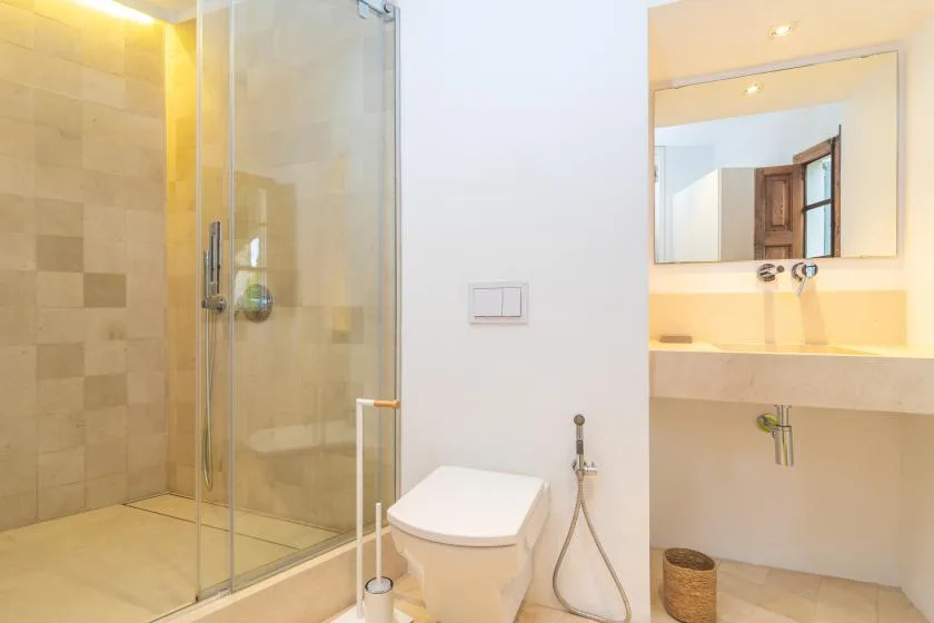 A bathroom with a glass shower, toilet, and sink.