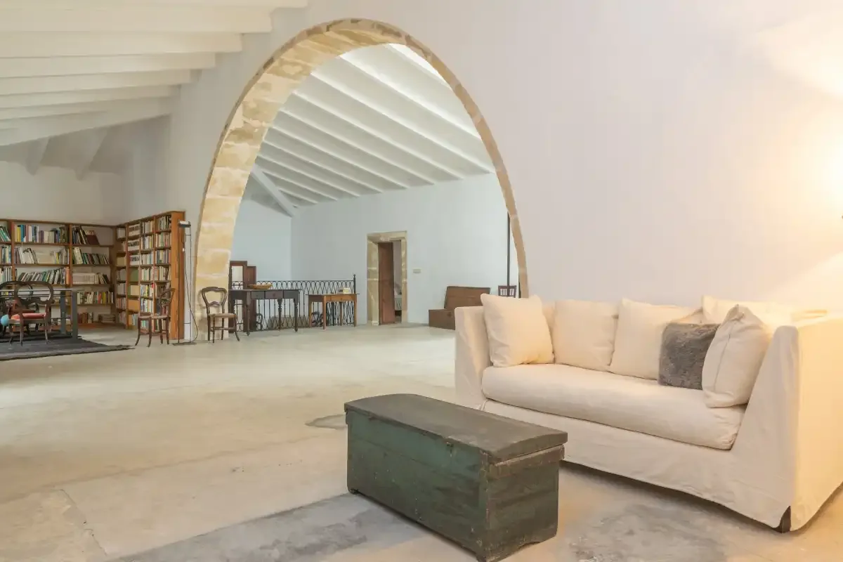 A spacious living area with a sofa and a large stone archway.