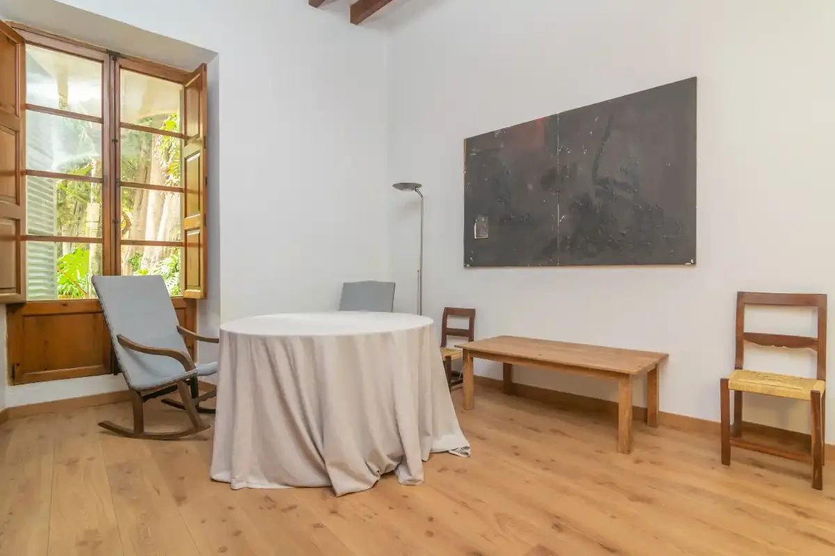 A bright dining area with a round table, wooden chairs, and a large window.
