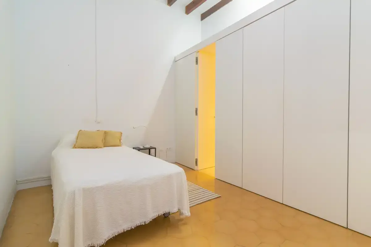 A bedroom with a bed beside a row of built-in cabinets.
