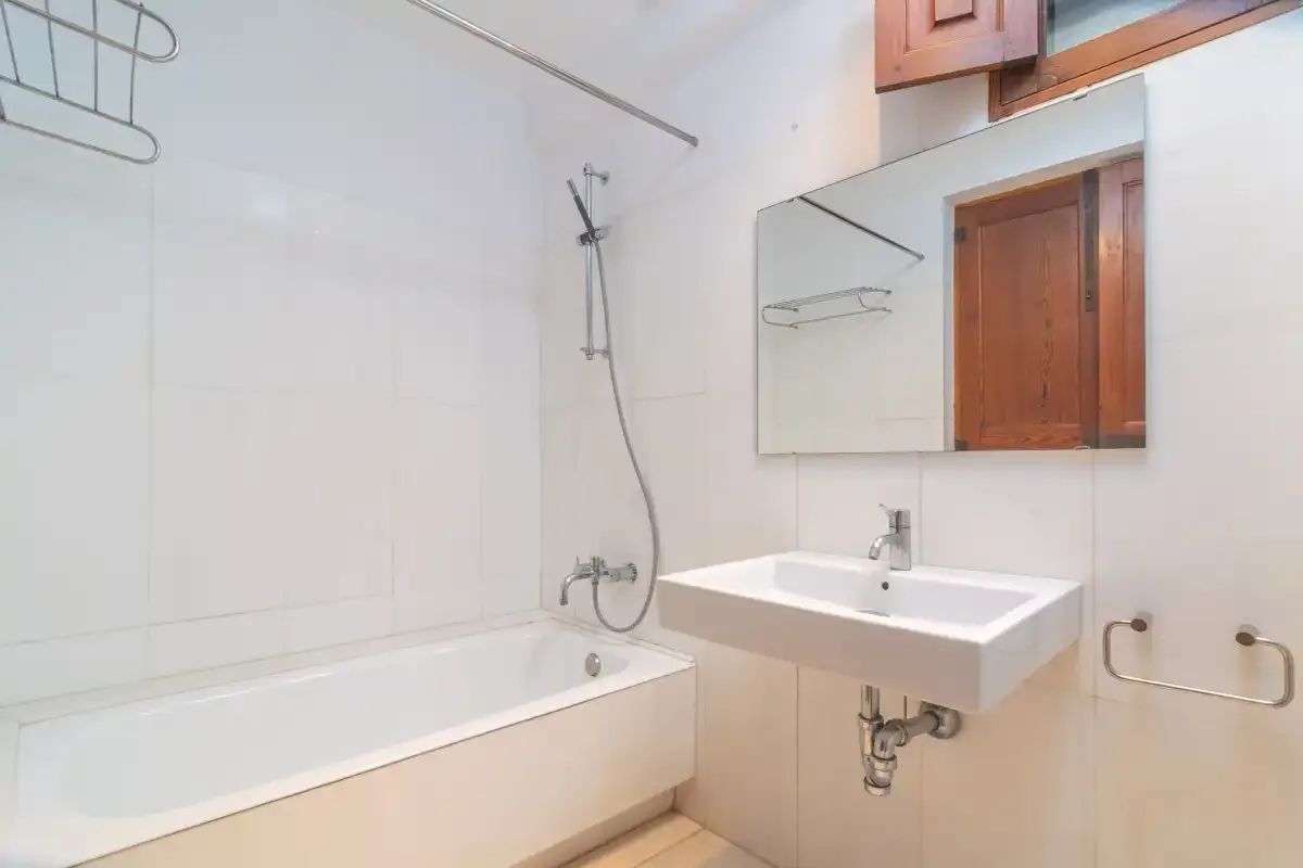 A bright bathroom with a bathtub, shower, and wall-mounted sink.