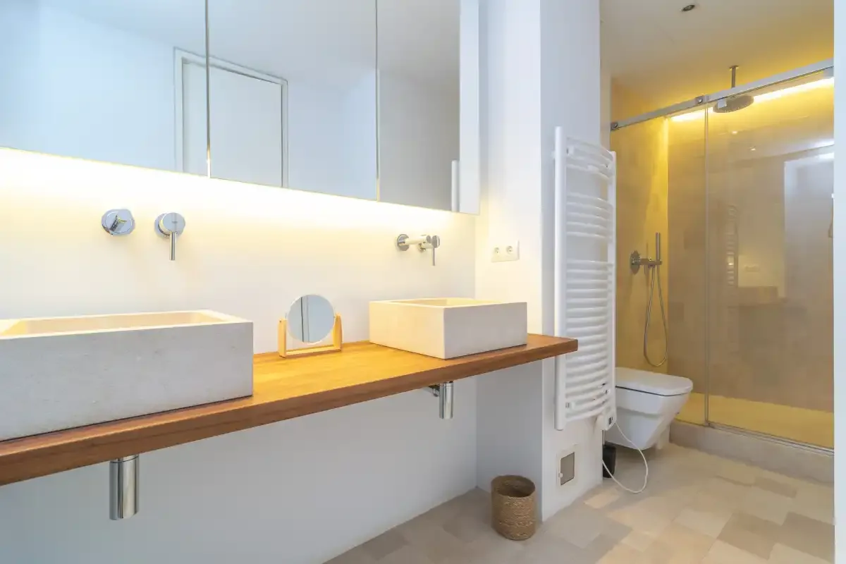 A bright bathroom with a long vanity and a glass shower.