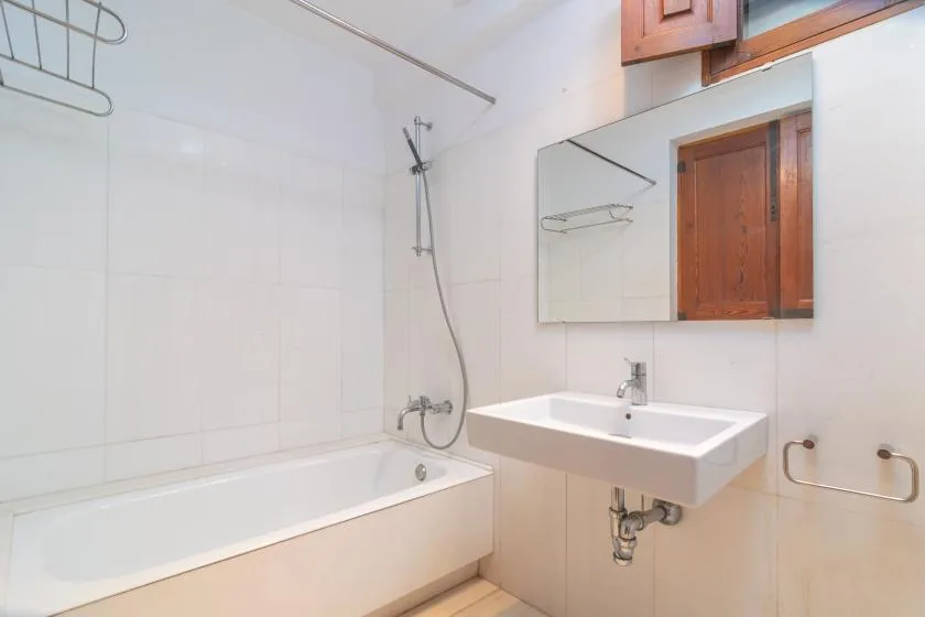 A bathroom with a bathtub, shower, and wall-mounted sink.