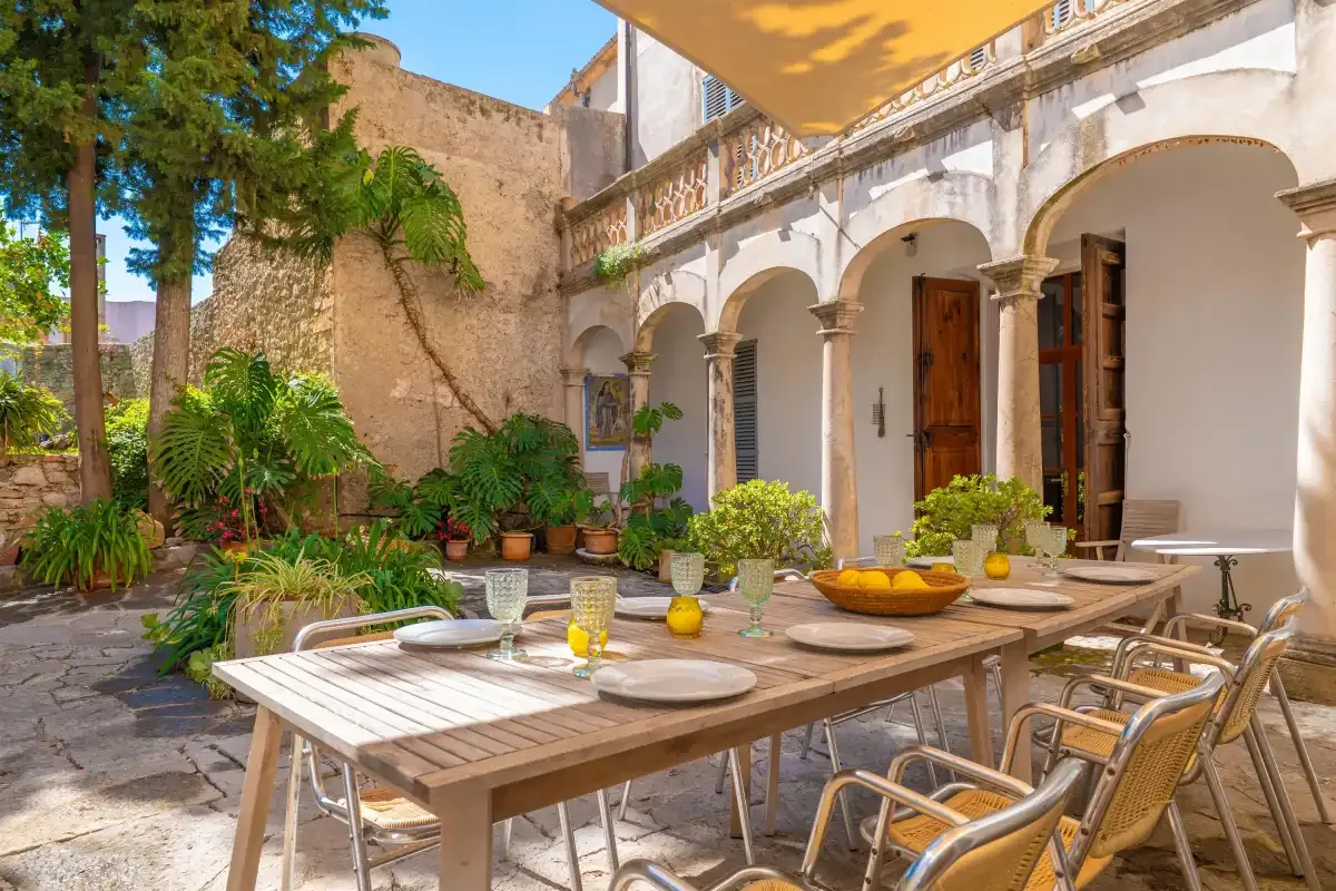 A courtyard dining area with a long table and potted plants.