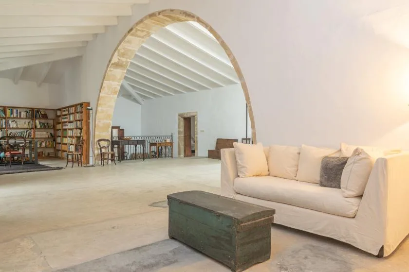 A spacious living room with pale seating and an arched opening.
