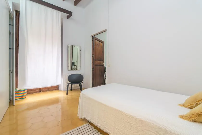 A bedroom with a bed, a chair, and a curtained window.