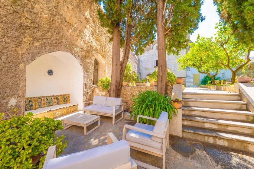A stone courtyard seating area with trees and steps leading to a garden.