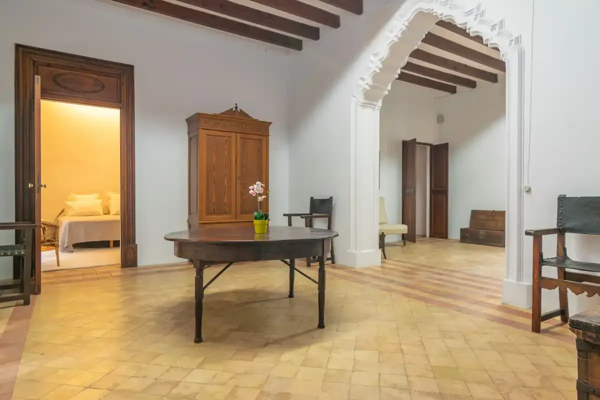 A spacious interior room with a central table and an arched opening.