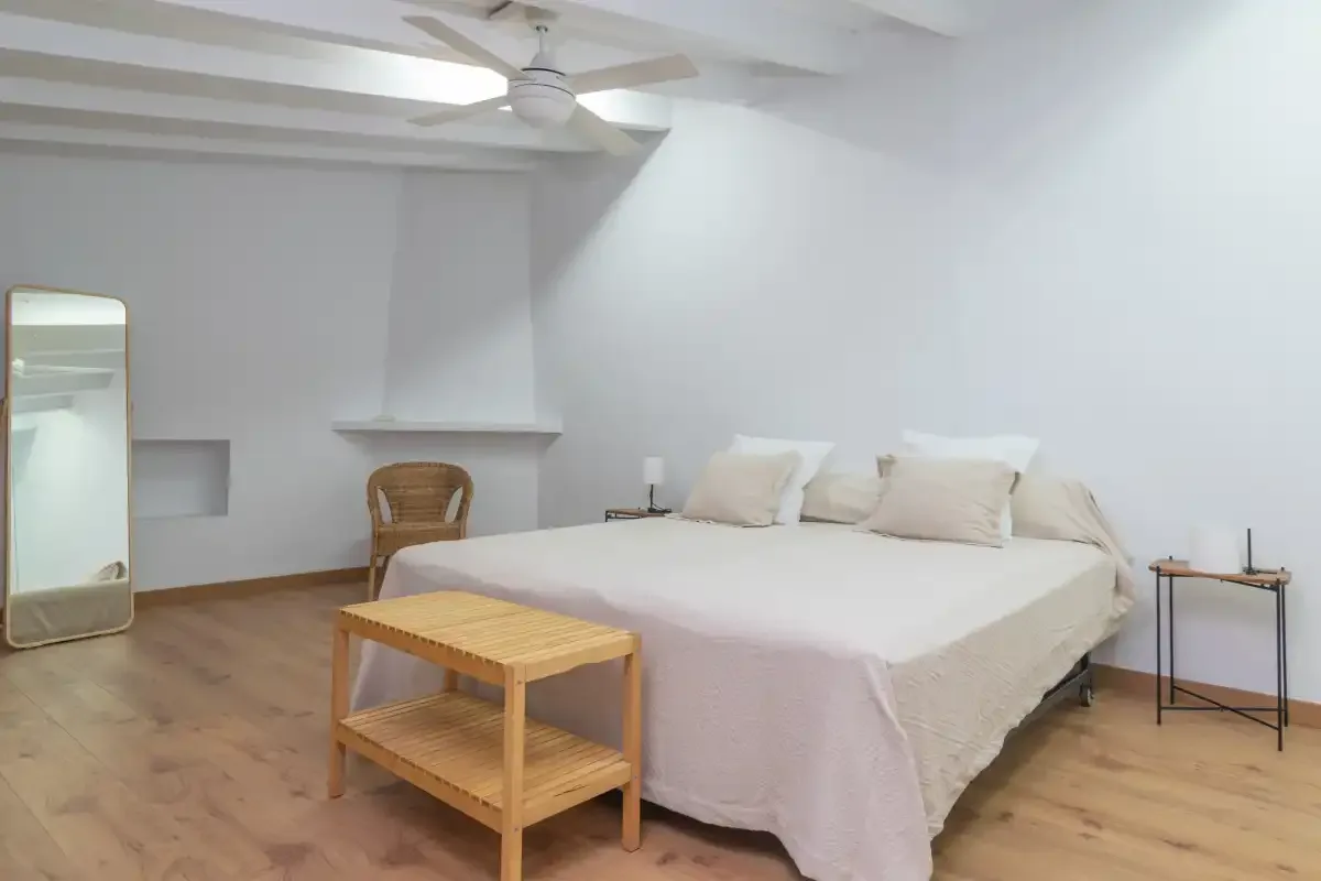 A bright bedroom with a large bed and a wooden table.