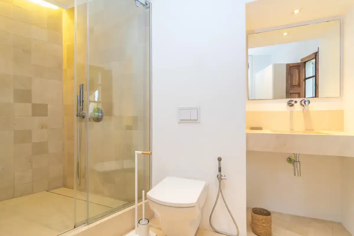 A bathroom with a glass shower, toilet, and sink.