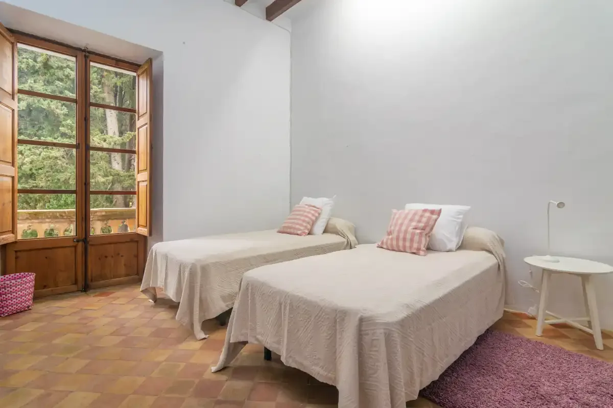 A bedroom with two beds and a large wooden-framed window.