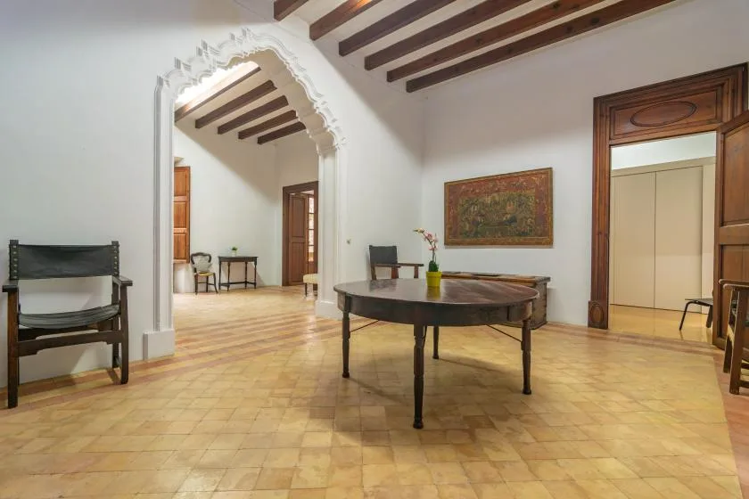 A spacious interior room with a central table and exposed ceiling beams.
