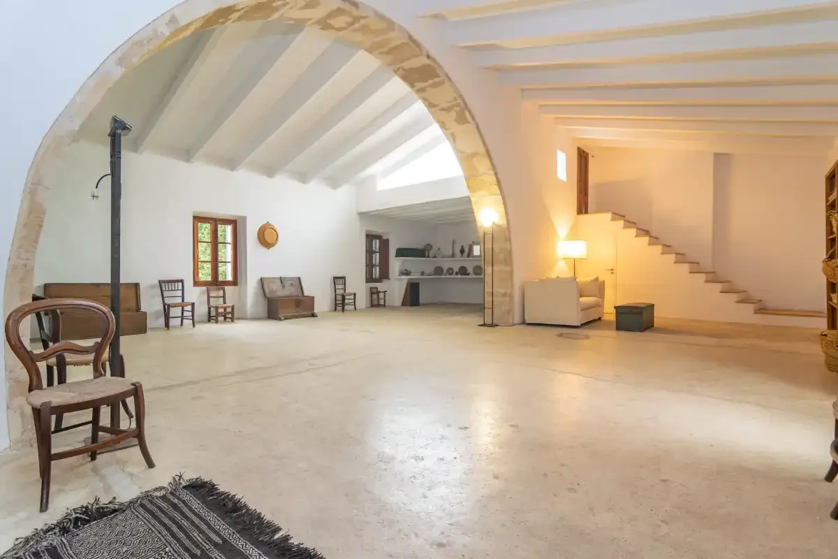 A spacious interior room with an arched opening and staircase.