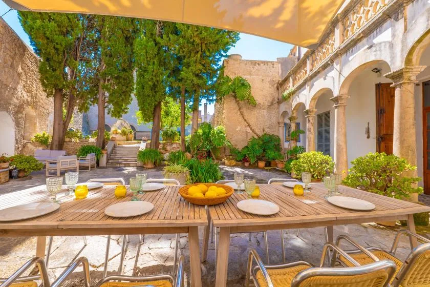 An outdoor patio with a long dining table beneath a shade canopy.