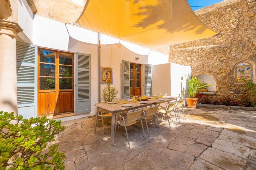 A sunlit outdoor dining area with a table beneath a fabric canopy.