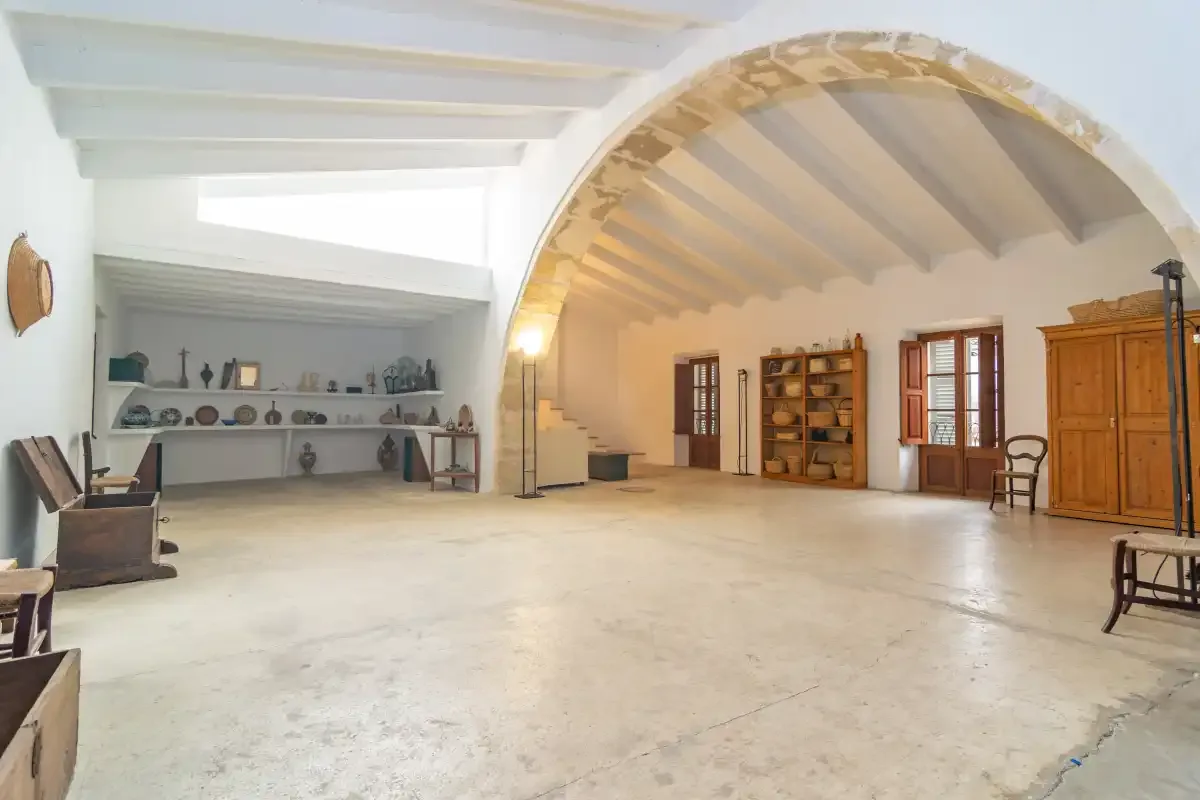 A spacious interior room with an arched opening and wooden furnishings.