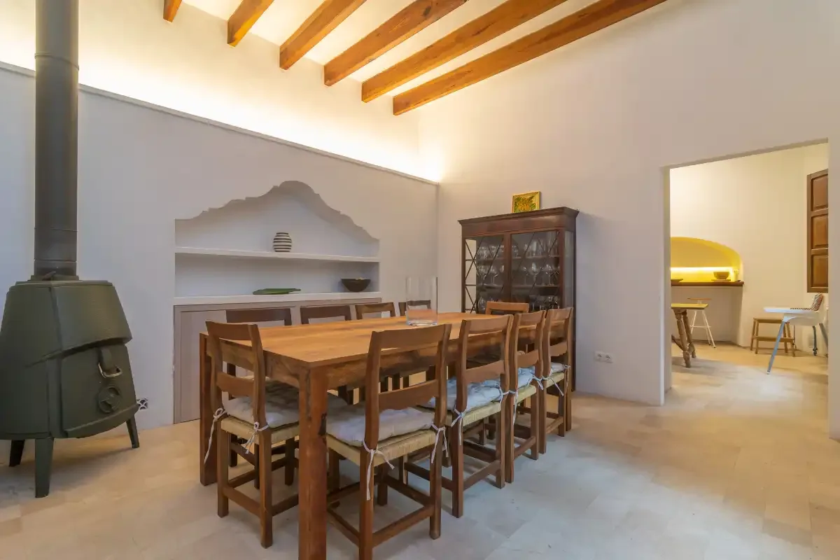 A dining area with a long wooden table, chairs, and a freestanding stove.