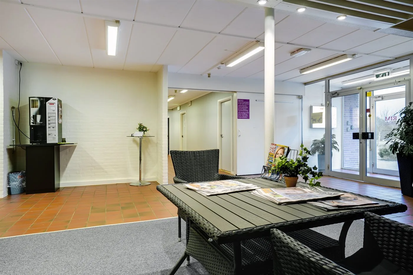 A bright lobby with a reception counter and seating by the glass entrance.