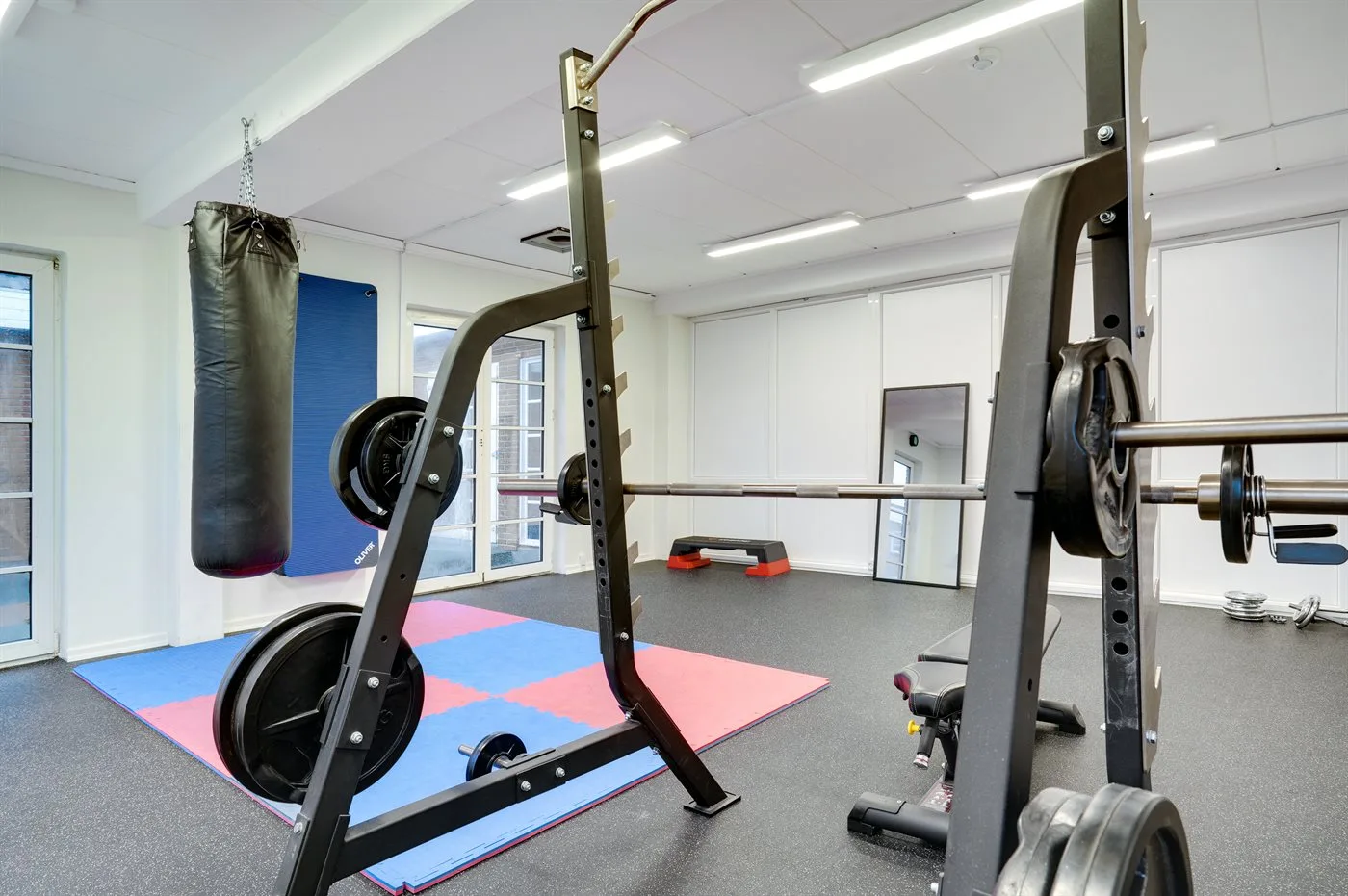 A gym with weight-training equipment and colorful floor mats.