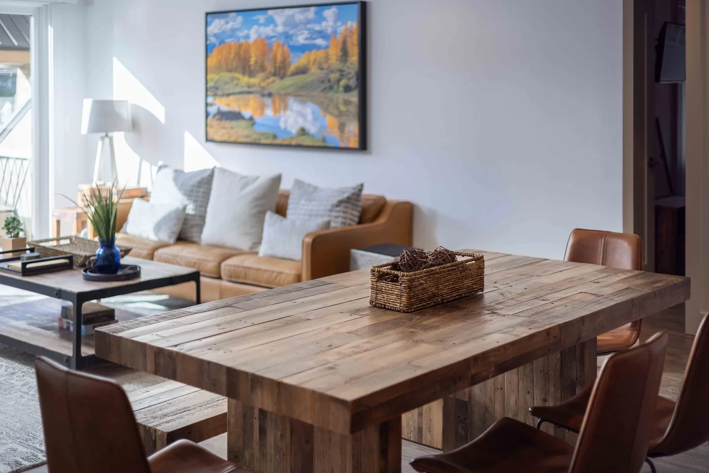 A bright living and dining area with a wooden table and seating.