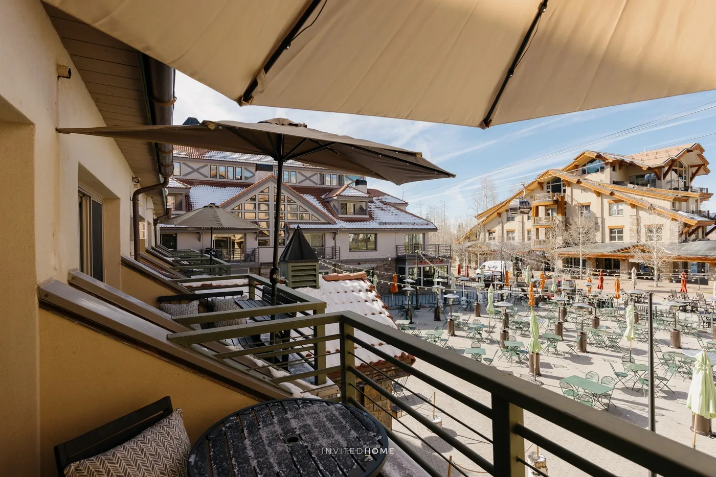 A balcony overlooks an outdoor seating area and surrounding buildings.