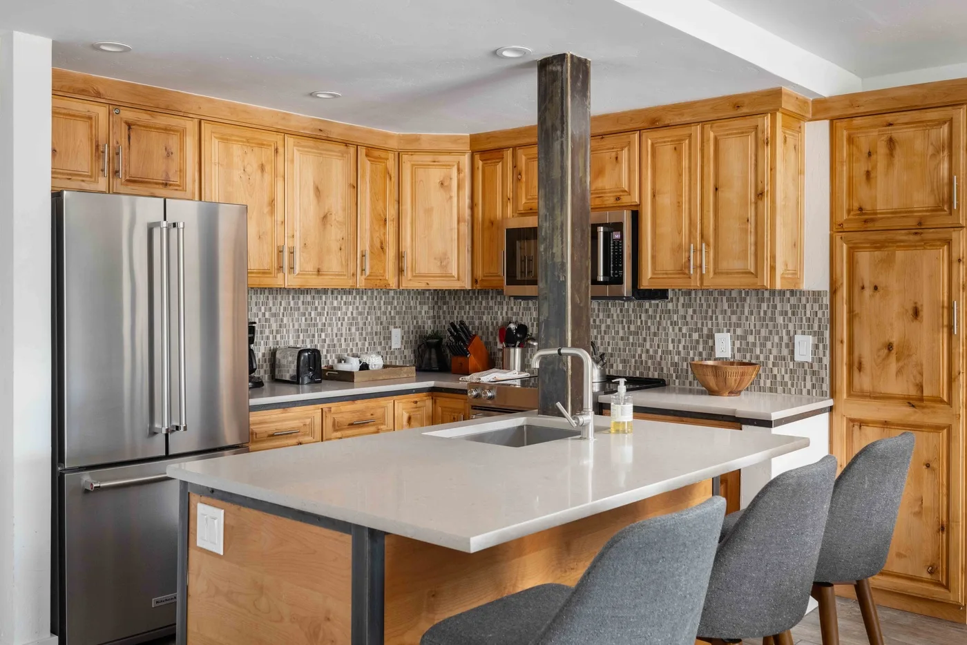A kitchen with wooden cabinets, stainless steel appliances, and a large island.