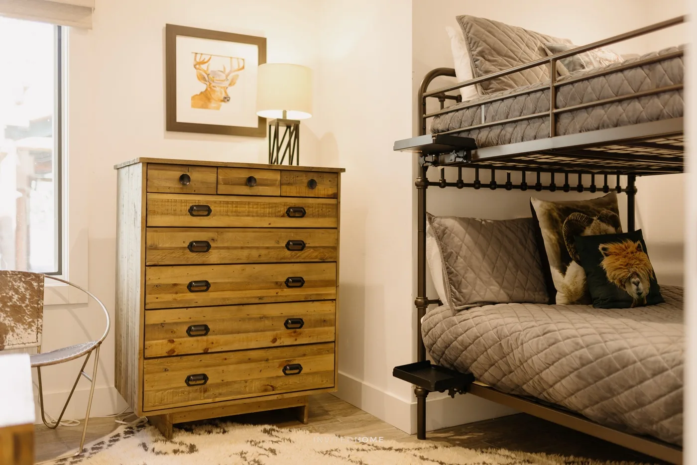 A bedroom with a wooden chest of drawers beside a bunk bed.