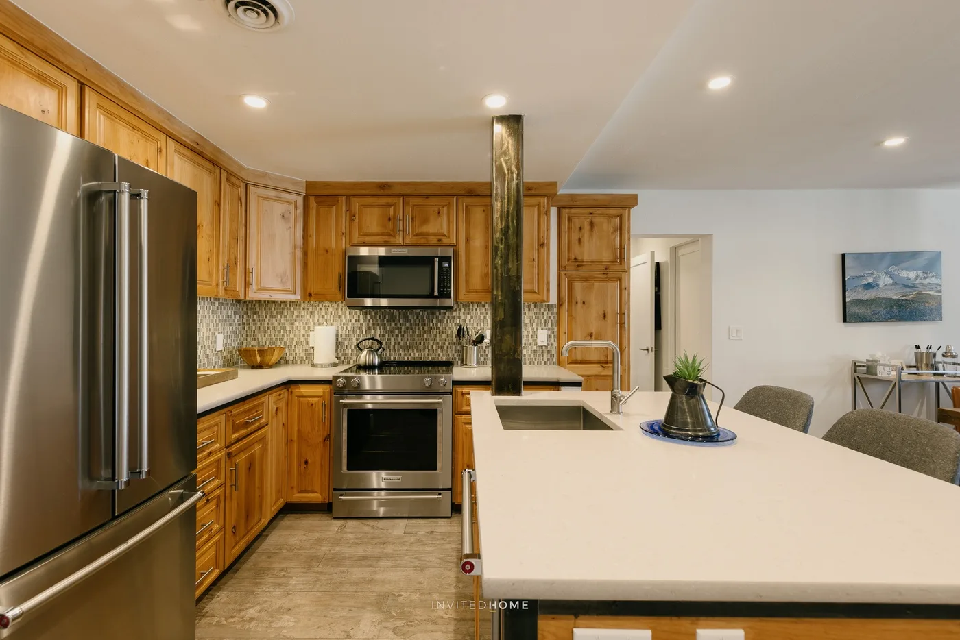 A kitchen with wooden cabinetry, stainless steel appliances, and a large island.