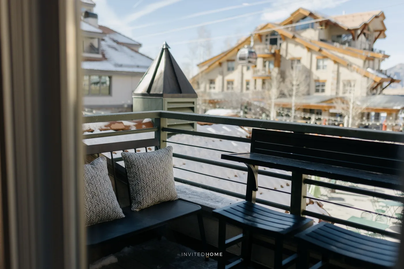A balcony seating area overlooks a snowy mountain resort building.