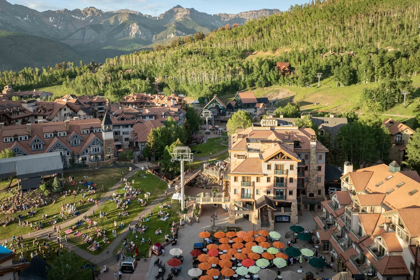 A mountain resort village with clustered buildings and colorful umbrellas in the foreground.