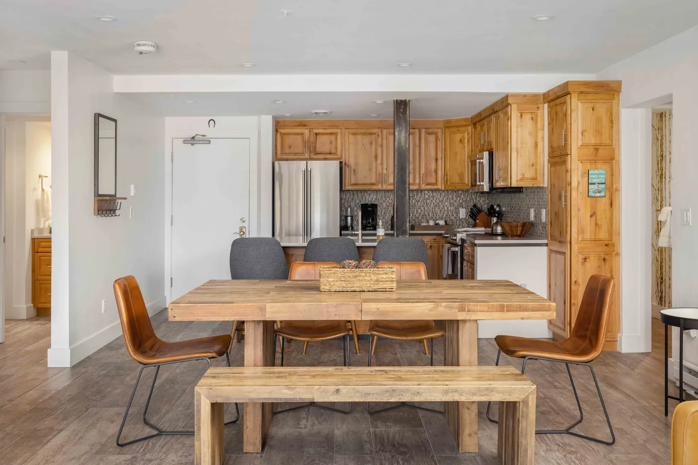 A dining area with a wooden table and seating in front of a kitchen.