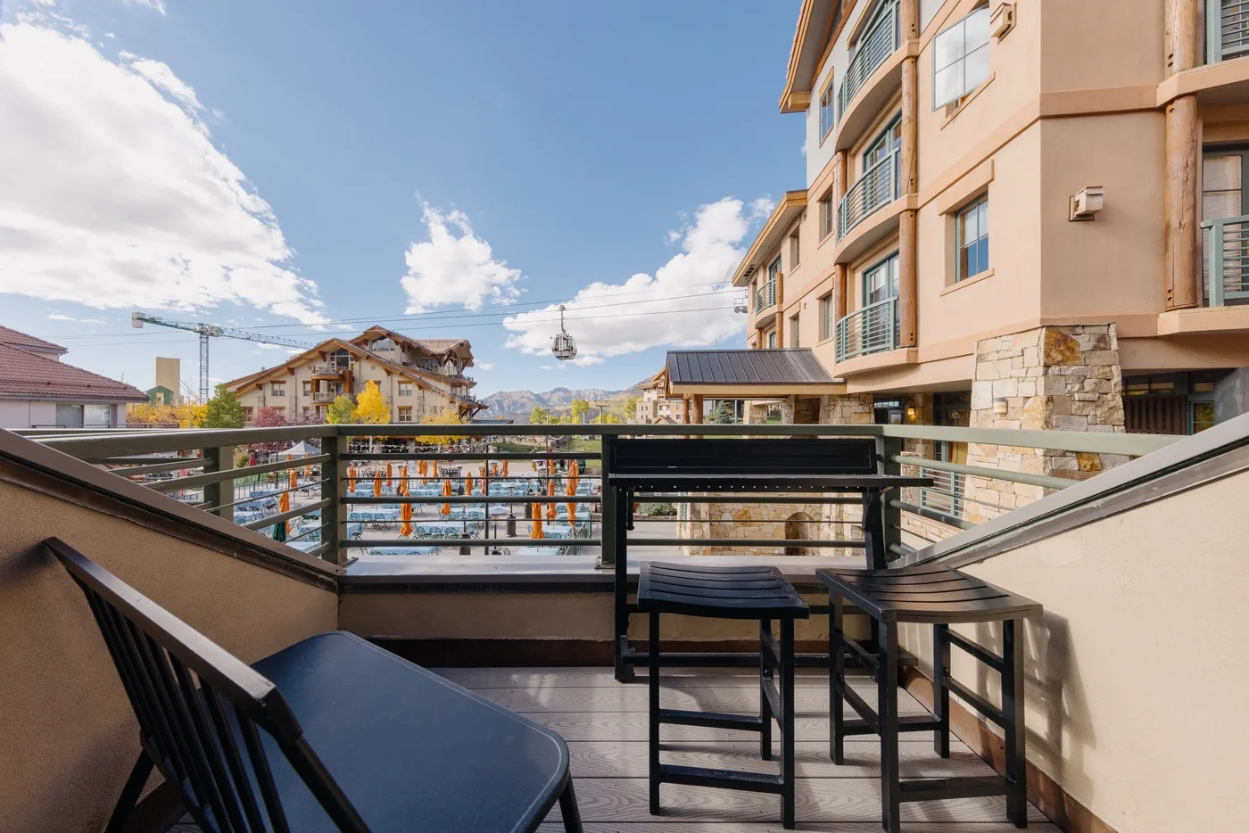 A balcony seating area overlooks nearby buildings beneath a blue sky.