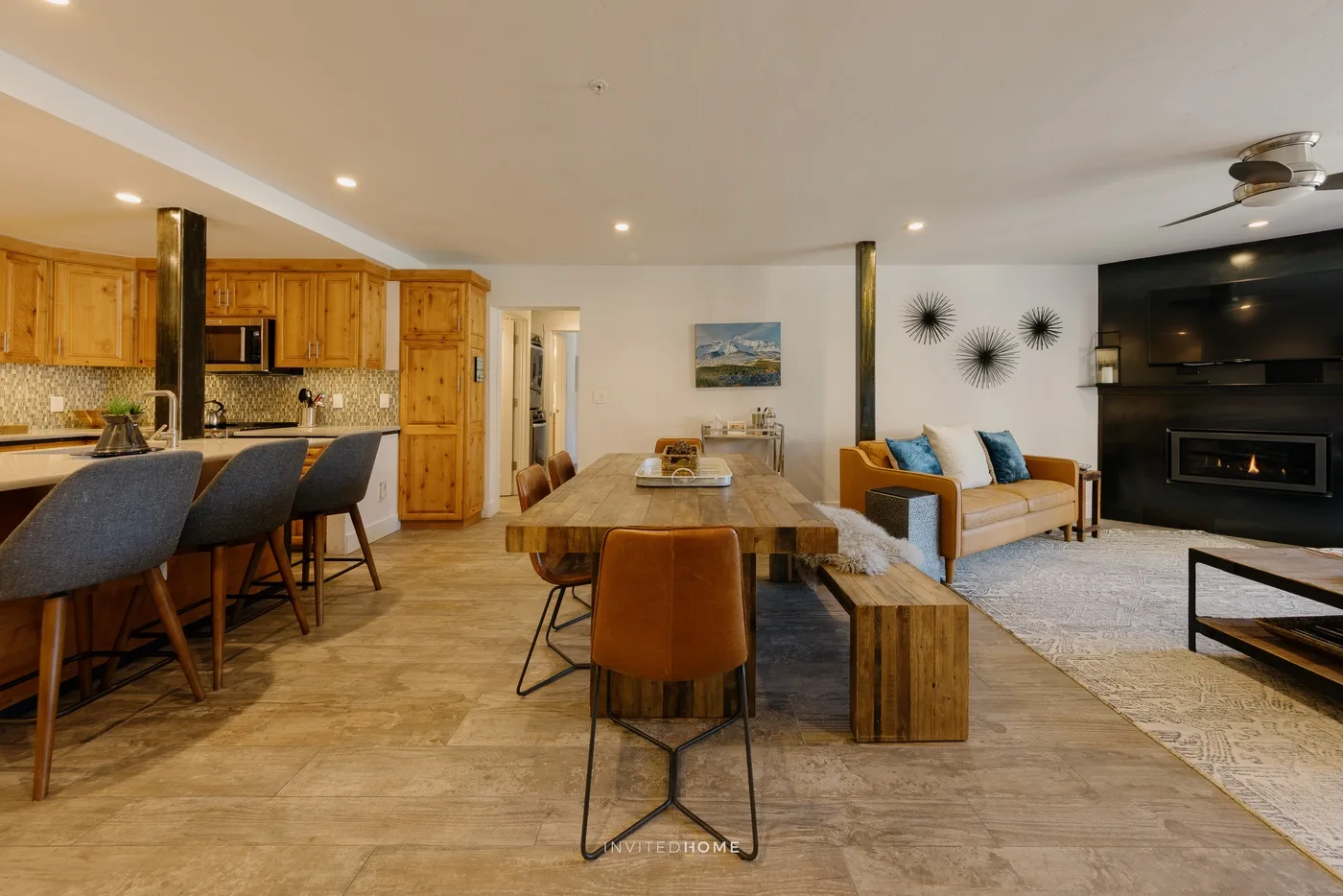 An open-plan living and dining area includes a kitchen counter and seating.